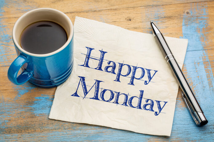 Happy Monday - cheerful handwriting on a napkin with a cup of c