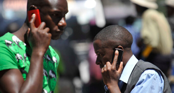 People use mobile phones in Nairobi, Kenya. There are about 700m sim cards in Africa.