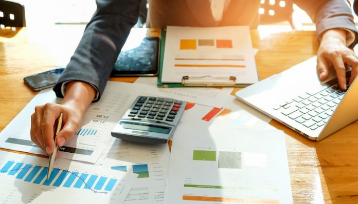 Businessman are analyzing graph data and use laptop computer to record data.